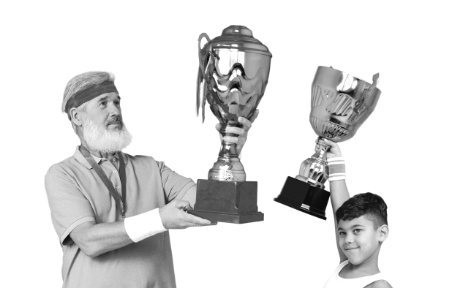 Ein älterer Mann und ein kleiner Junge halten einen Pokal hoch